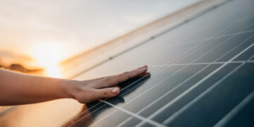 Close-up of human hand touching solar panel during Sunset